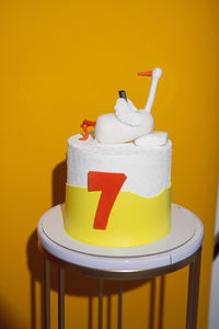 A cake with a goose lying on a pillow with a phone on a yellow background