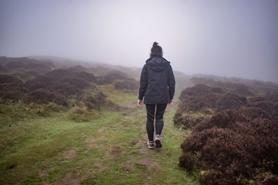 Rear view of woman walking into fog