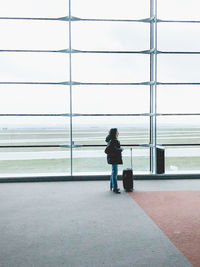 Rear view of woman walking on airport against sky