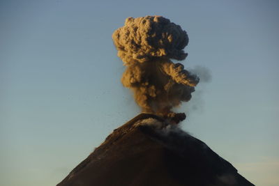 Low angle view of smoke emitting from volcanic against blue sky