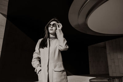 Fashionable woman wearing sunglasses while standing on footpath during sunny day