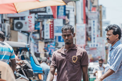 Portrait of friends standing on street market in city