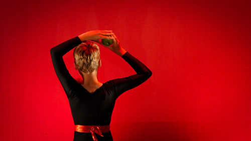 Woman standing against red wall