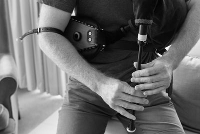 Midsection of man holding bagpipe