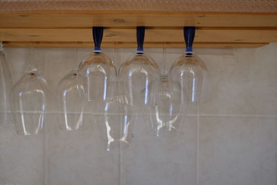 Upside down image of wineglasses on table against tiled wall