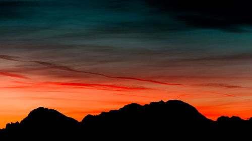 Silhouette mountains against dramatic sky during sunset