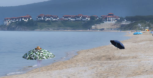 People on beach by sea against buildings