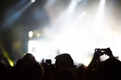 Rear view of people photographing at music concert