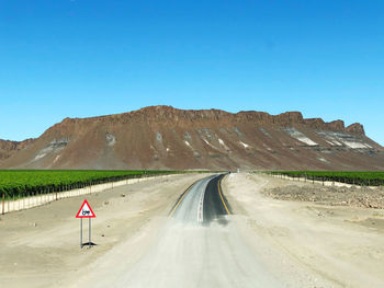 Road amidst landscape against clear blue sky