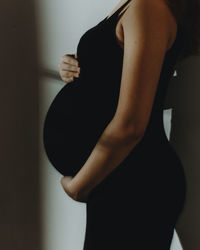 Side view of woman standing against wall at home