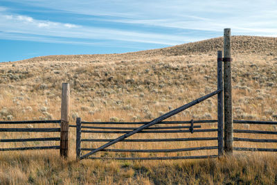 Wooden fence on field against sky