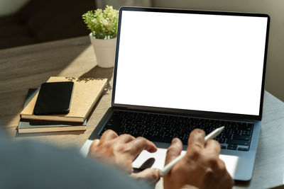 Cropped hands using laptop at table