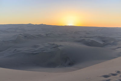 Scenic view of desert against sky during sunset