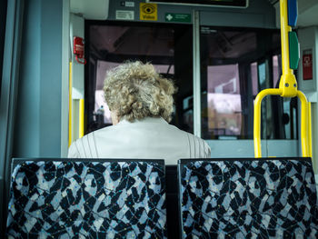 Rear view of senior woman sitting on tram in berlin