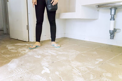 Low section of woman standing on dirty tiled floor