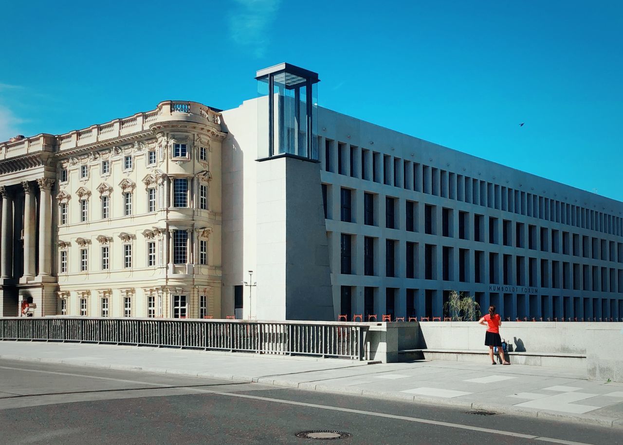 building exterior, built structure, architecture, city, building, sky, nature, day, blue, men, real people, sunlight, people, clear sky, walking, lifestyles, outdoors, incidental people, travel destinations, full length, office building exterior