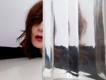 Close-up portrait of woman looking through glass window