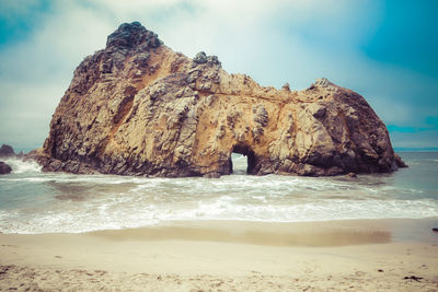 Rock formation on beach against sky