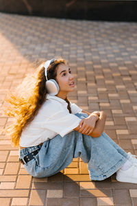 Portrait of young woman sitting on footpath