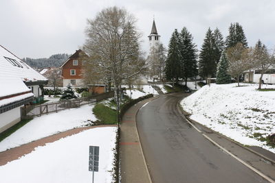 Snow covered street amidst houses and trees during winter
