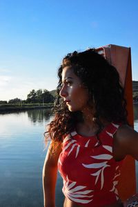 Woman looking away while standing against sky