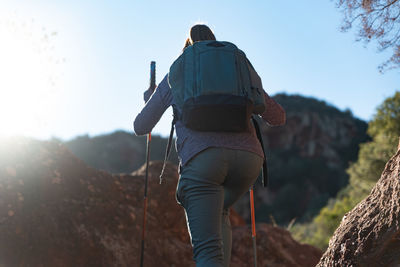 Woman climbs the mountain in the garraf natural park, supported by hiking sticks.