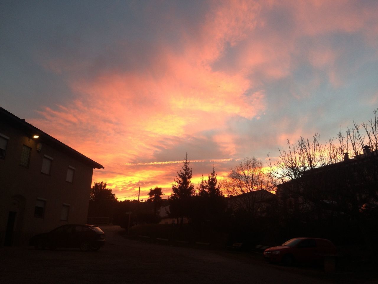 sunset, sky, silhouette, orange color, cloud - sky, road, transportation, tree, street, car, building exterior, land vehicle, built structure, cloud, architecture, beauty in nature, nature, scenics, power line, house