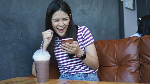 Young woman looking away while sitting on table