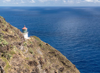 Lighthouse by sea against sky