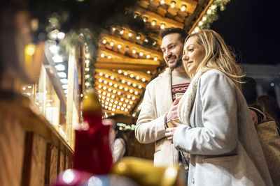 Happy young woman and man shopping at christmas market