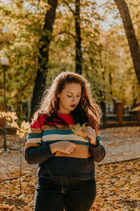 Beautiful young woman standing in park during autumn