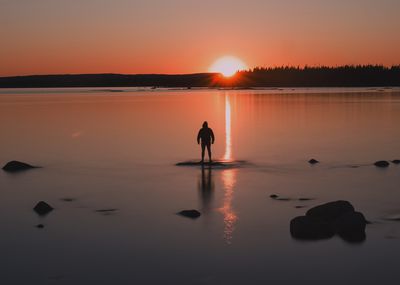 Silhouette woman walking on beach against sky during sunset