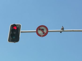 Low angle view of stoplight against clear blue sky