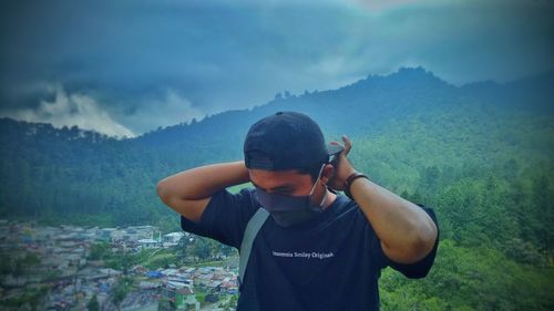 Young man standing on mountain against sky