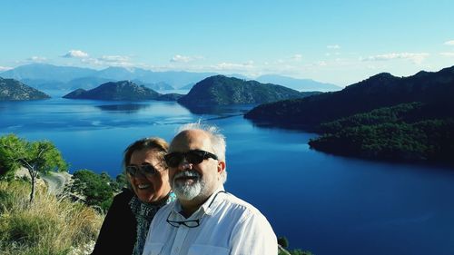 Portrait of smiling couple wearing sunglasses while standing against island