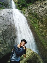 Full length of smiling young woman on rock