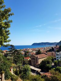 Town by sea against clear blue sky