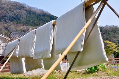 Clothes drying on clothesline on field against sky