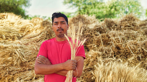 Portrait of young woman standing on hay