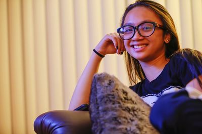 Portrait of smiling teenage girl sitting on sofa at home