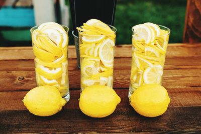 Slices in glasses by lemons on wooden table