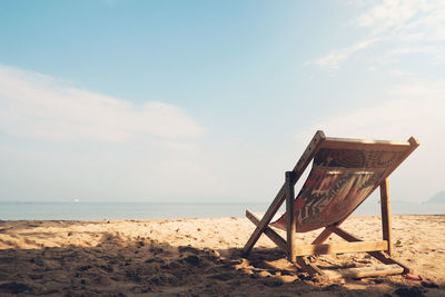 Chair on beach against sky