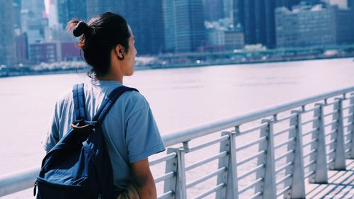 Young woman standing by railing in city