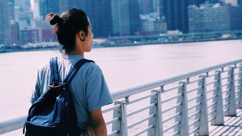 Young man standing by railing in city