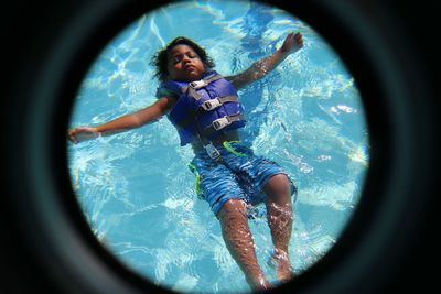 Portrait of boy wearing life jacket while swimming in sea