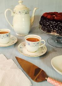 High angle view of tea cups and chocolate cake on table