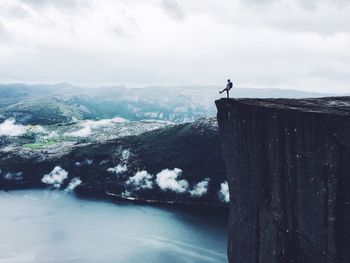 Mid distance view of person standing at the edge of cliff by sea