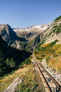 Railroad track amidst mountains against clear sky