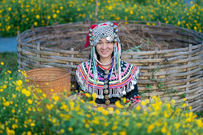 Portrait of smiling woman standing by flowering plants on field