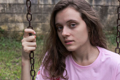 Portrait of young woman swinging at playground